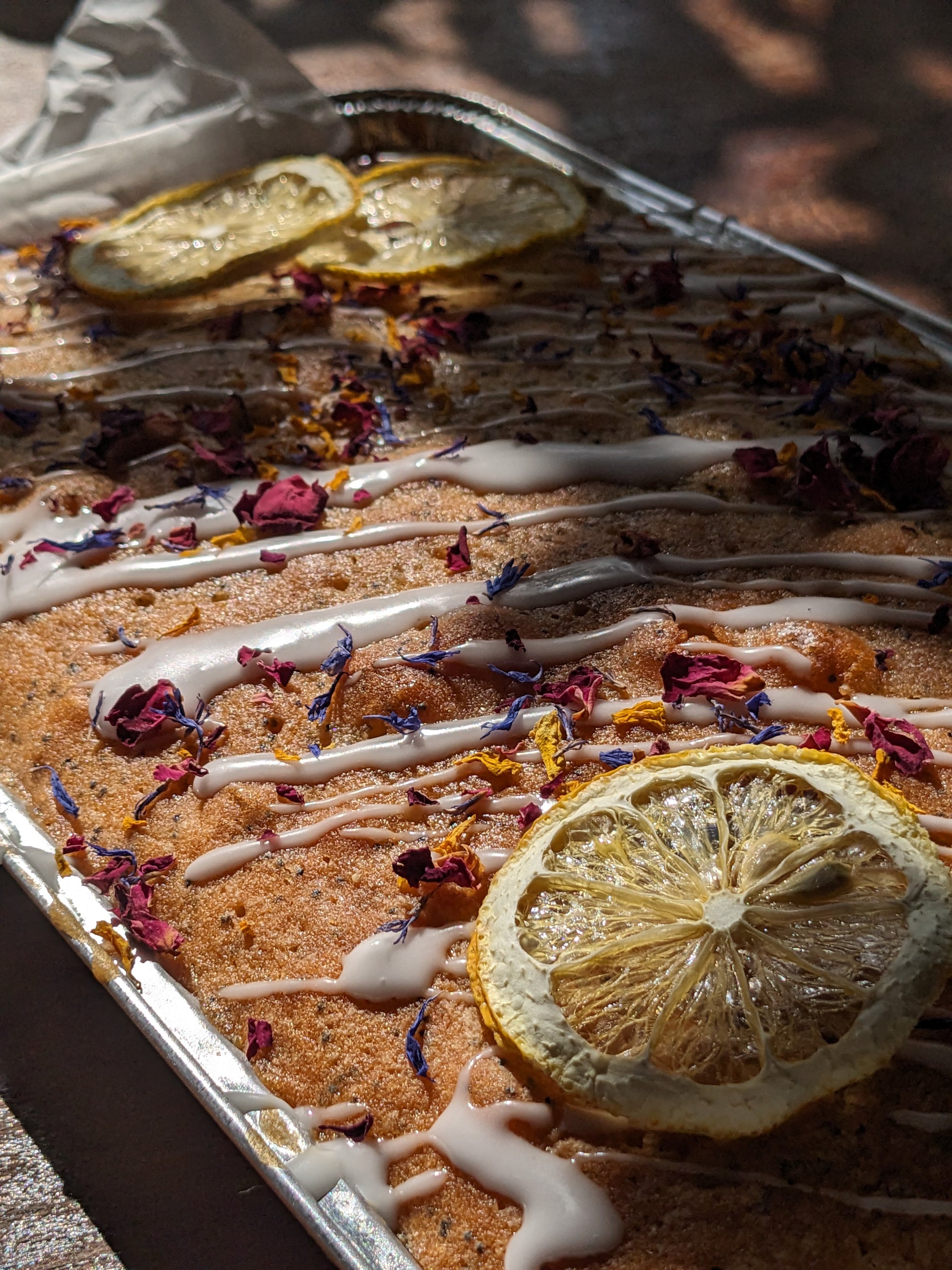 Baked good with lemon slices and dried flowers on a baking tray