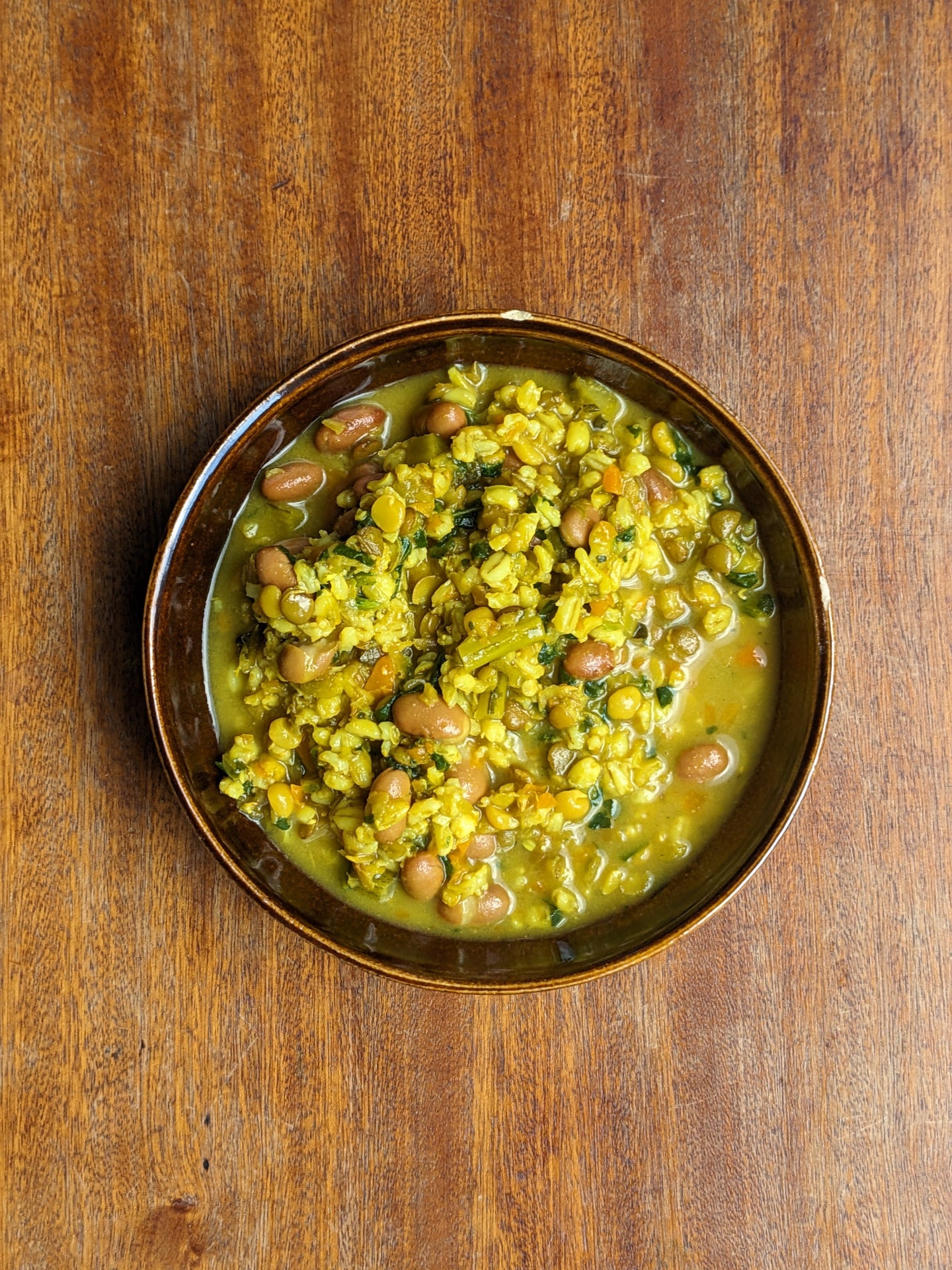 Overhead view of my multigrain turmeric soup, bright and golden with visible grains and spices.