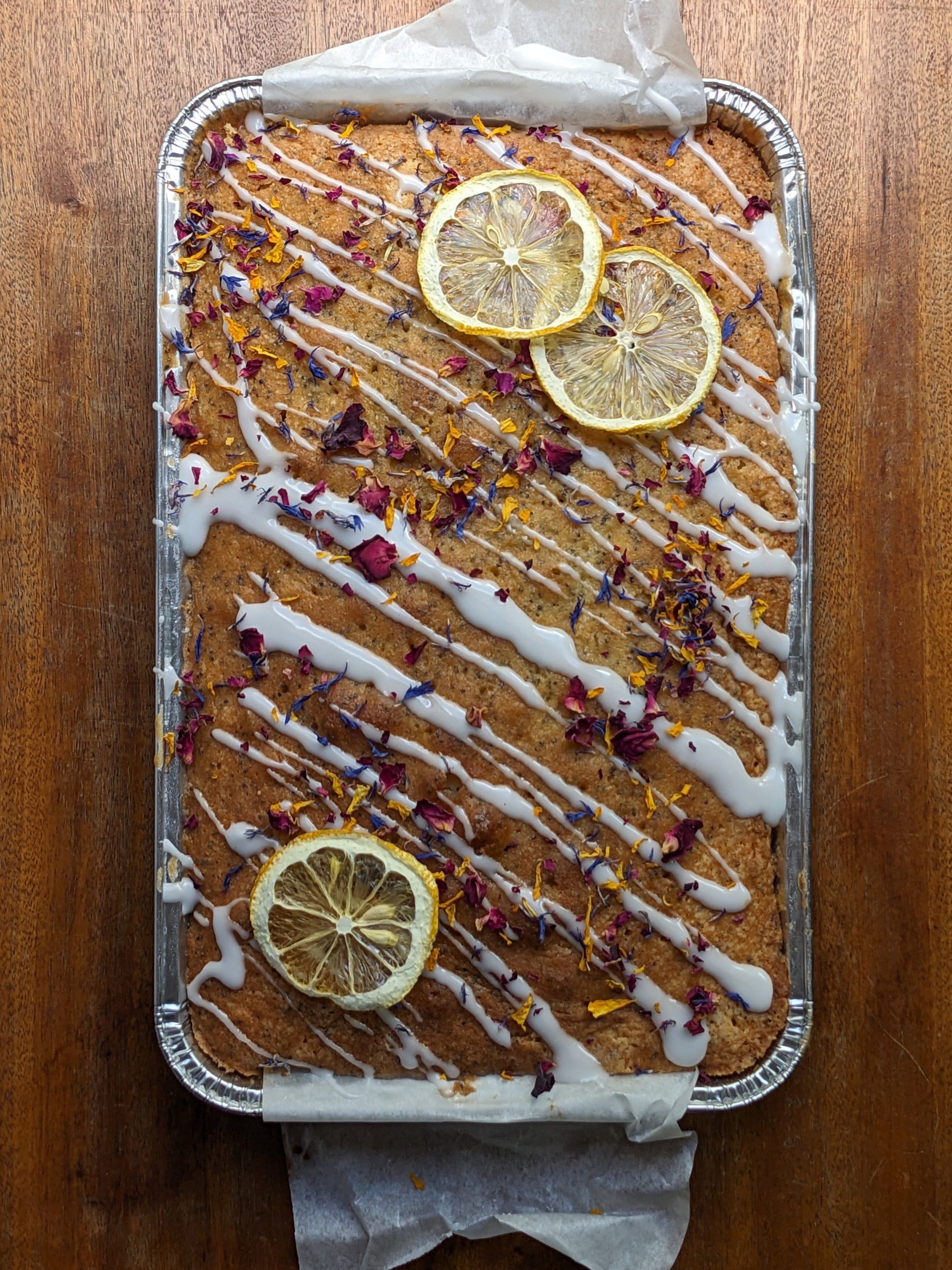 Sheet cake with lemon slices and white drizzle on a wooden surface