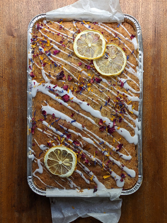Sheet cake with lemon slices and white drizzle on a wooden surface