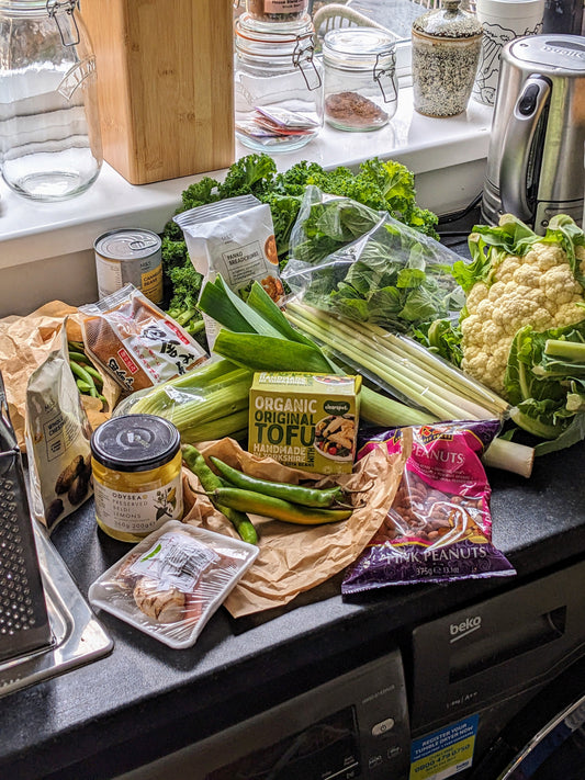 Groceries including fresh fruits, vegetables, tofu and legumes on a kitchen countertop