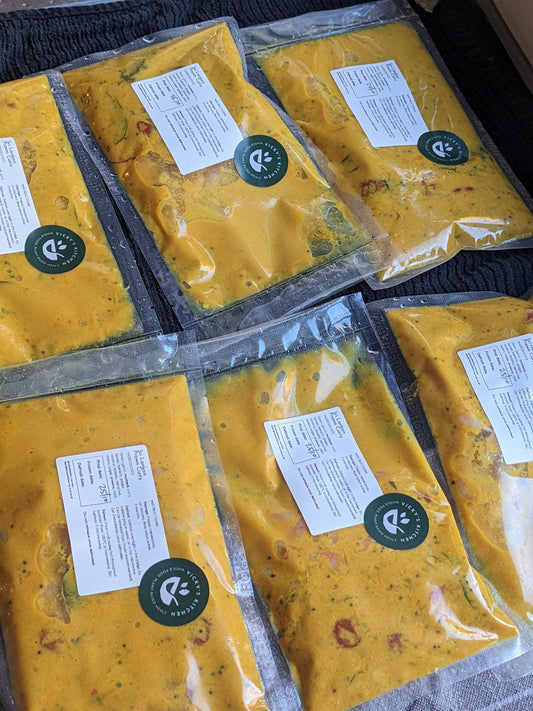 Multiple packages of yellow food with labels and a brand logo on a dark surface.