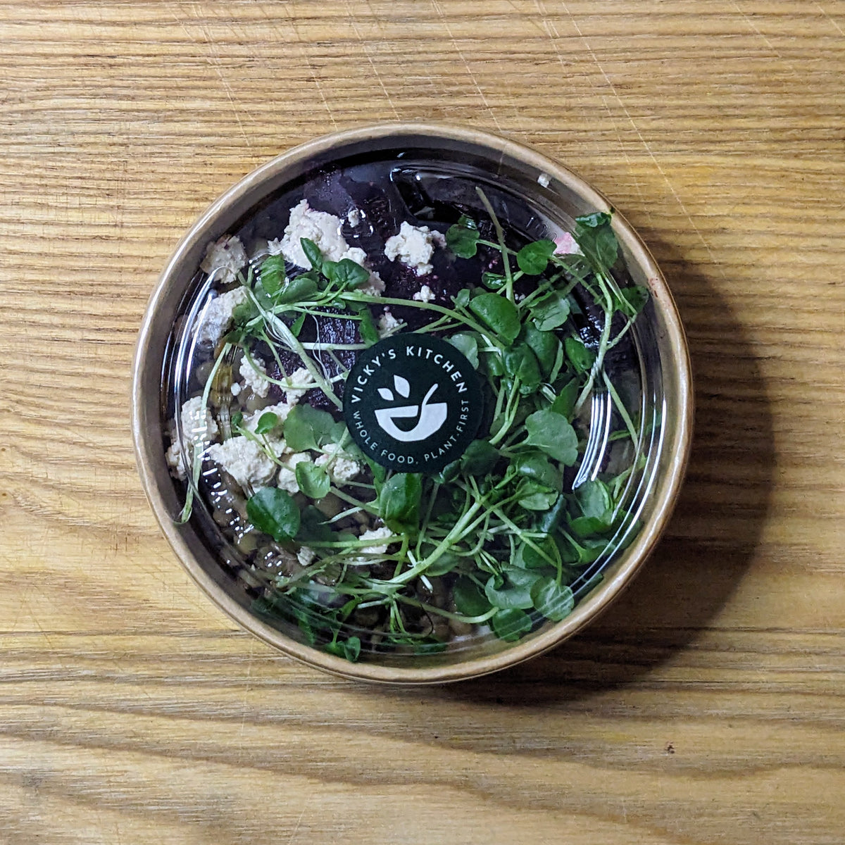 Bowl of salad with greens and croutons on a wooden surface